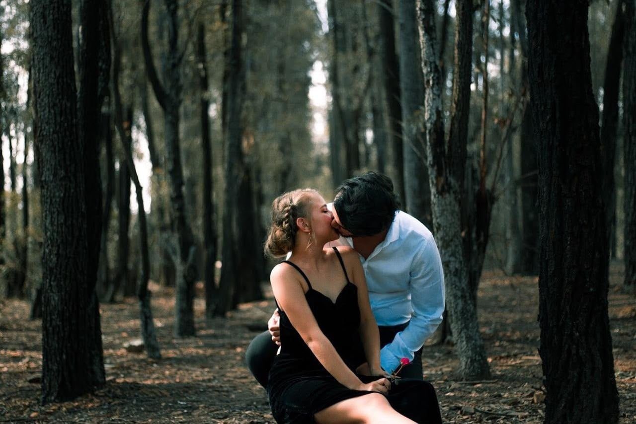 Ian and Chavón sitting close together on the forest floor.
